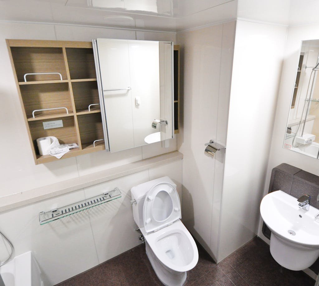 A contemporary bathroom with a toilet, sink, and storage shelves featuring a minimalist design.