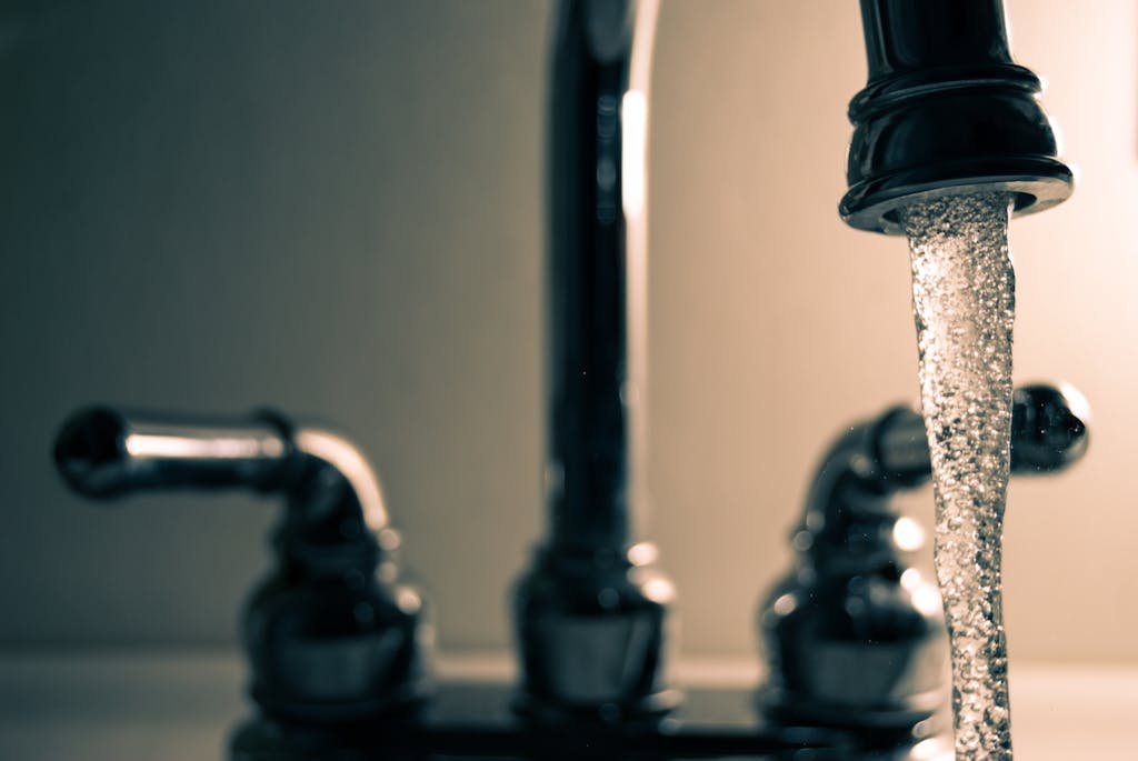 A detailed shot of water flowing from a steel faucet, ideal for themes on cleanliness or plumbing.