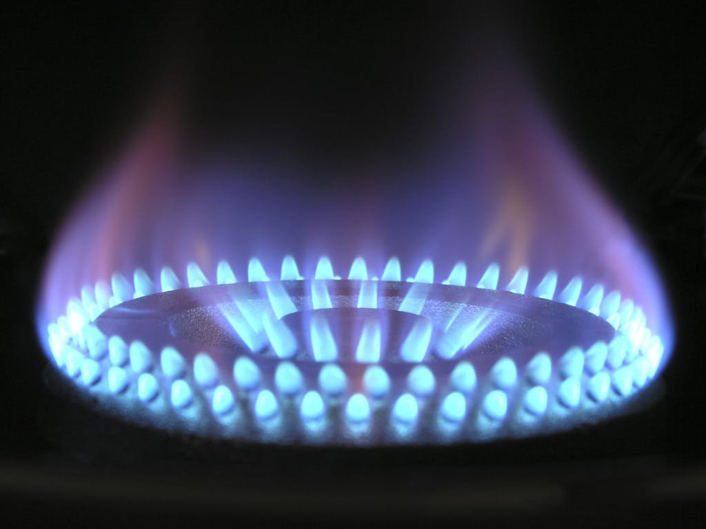 A detailed view of a blue flame on a gas stove, illustrating heat and warmth.